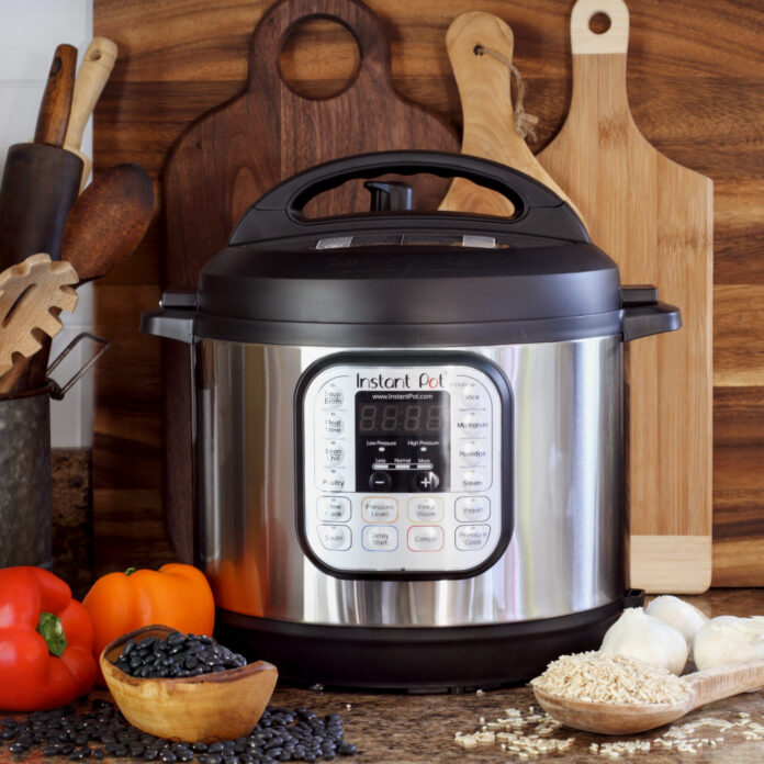 Pot pressure cooker on kitchen counter with beans and rice.
